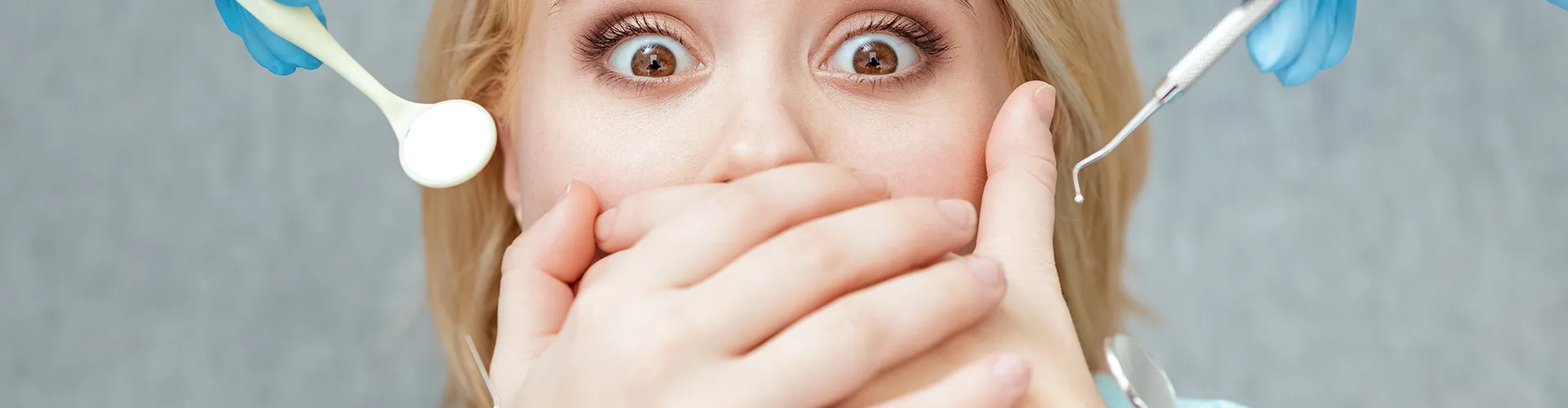 Gloved hands holding dental tools around woman covering her mouth.