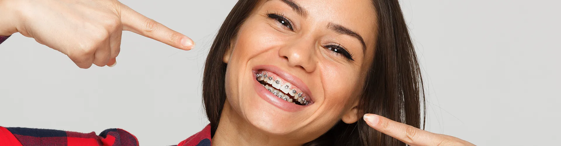 Smiling woman pointing at her dental braces.