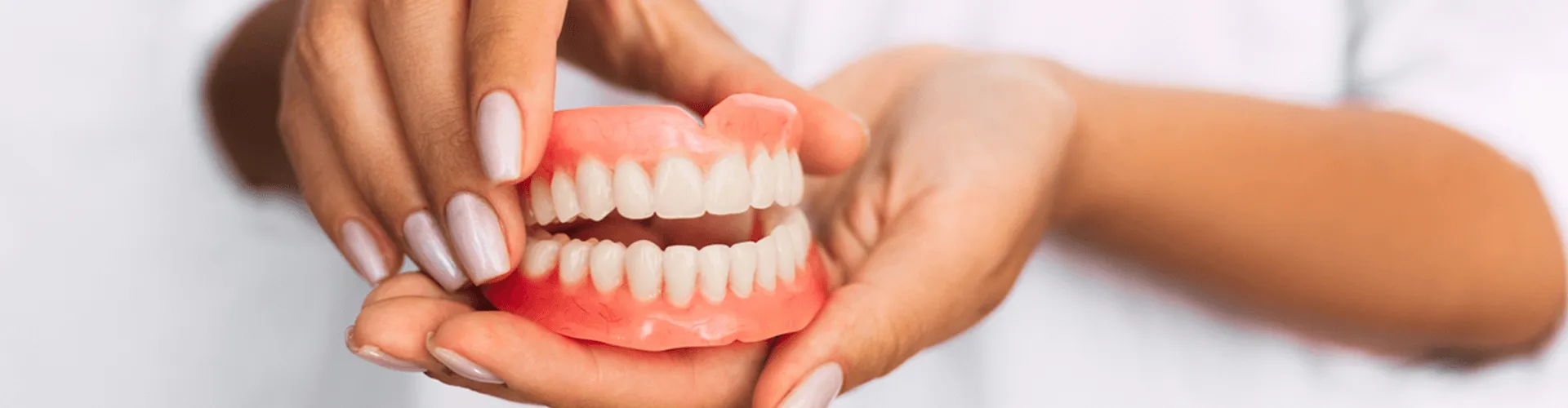Hands holding a pair of dentures.