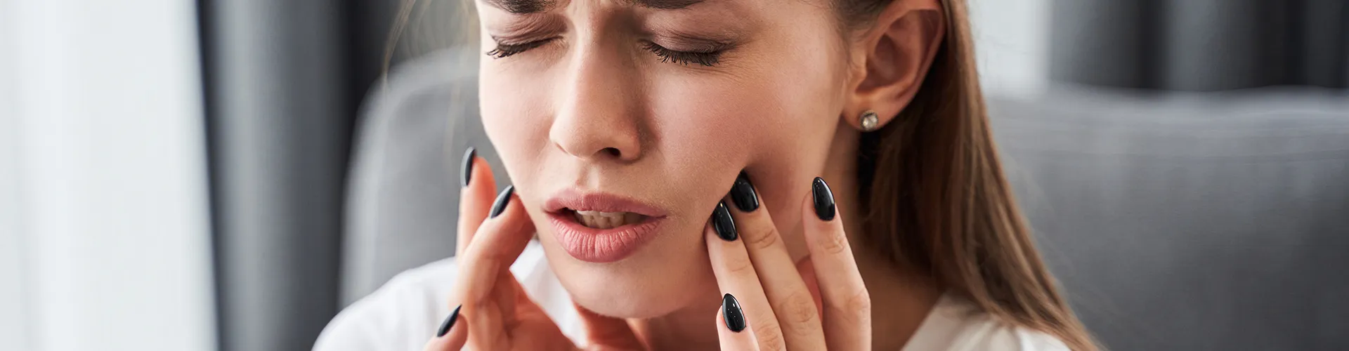 A woman showing discomfort from a toothache.