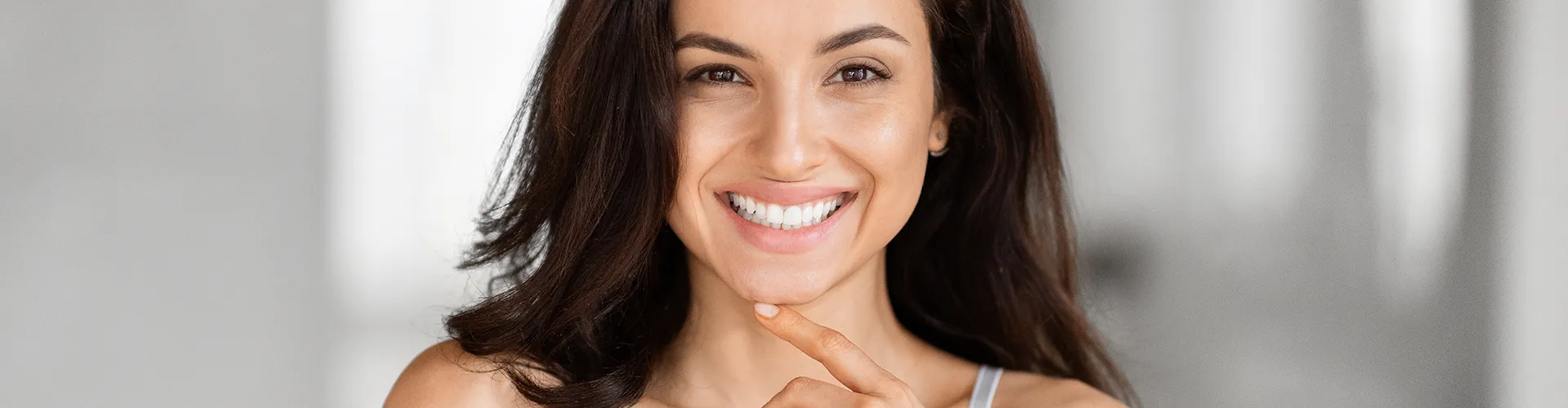 Smiling woman with her finger on her chin.