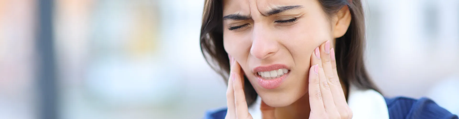 A woman holding her cheeks with her hands, showing discomfort.