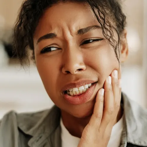 Woman holding her cheek in pain.