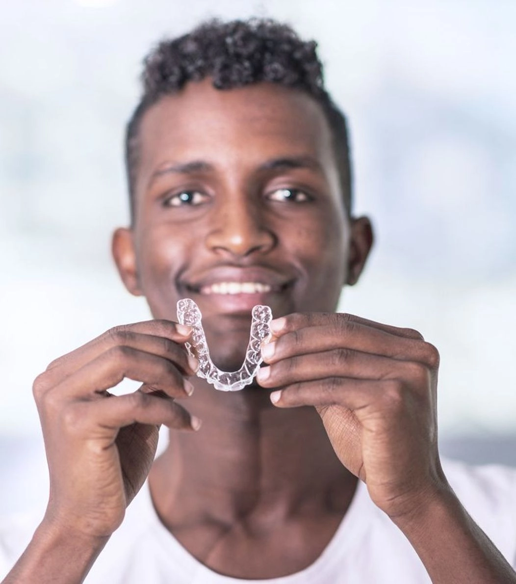 An image of a man holding Invisalign aligners