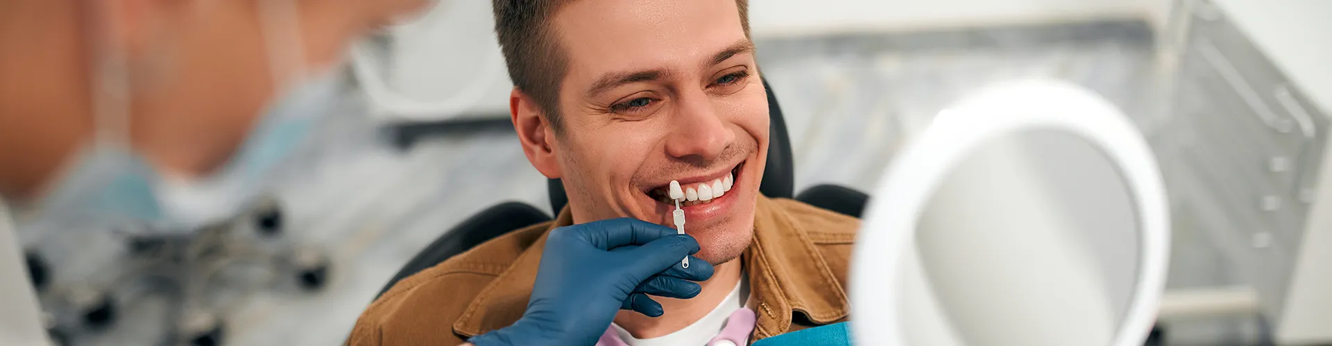Man in dental office having veneers matched to his teeth.