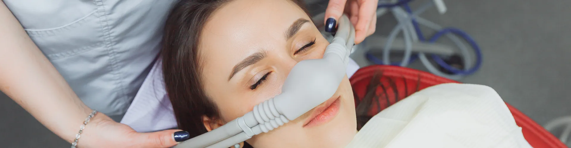 Hands placing a sedation mask over a patient's nose.