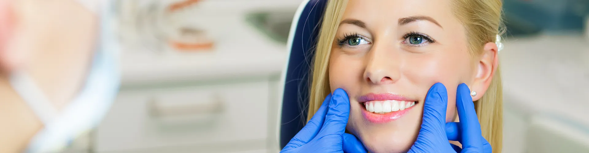 Gloved hands holding smiling woman's cheeks.