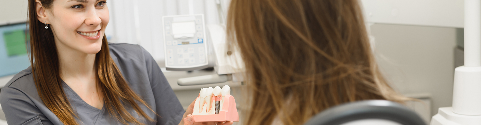Dentist showing patient model of dental implant.