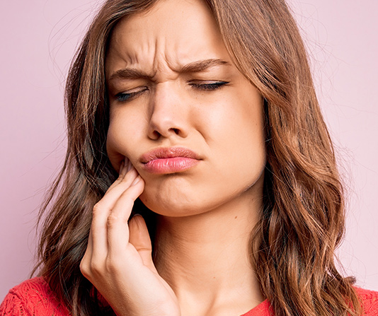 Woman clutching jaw experiencing tooth or gum pain