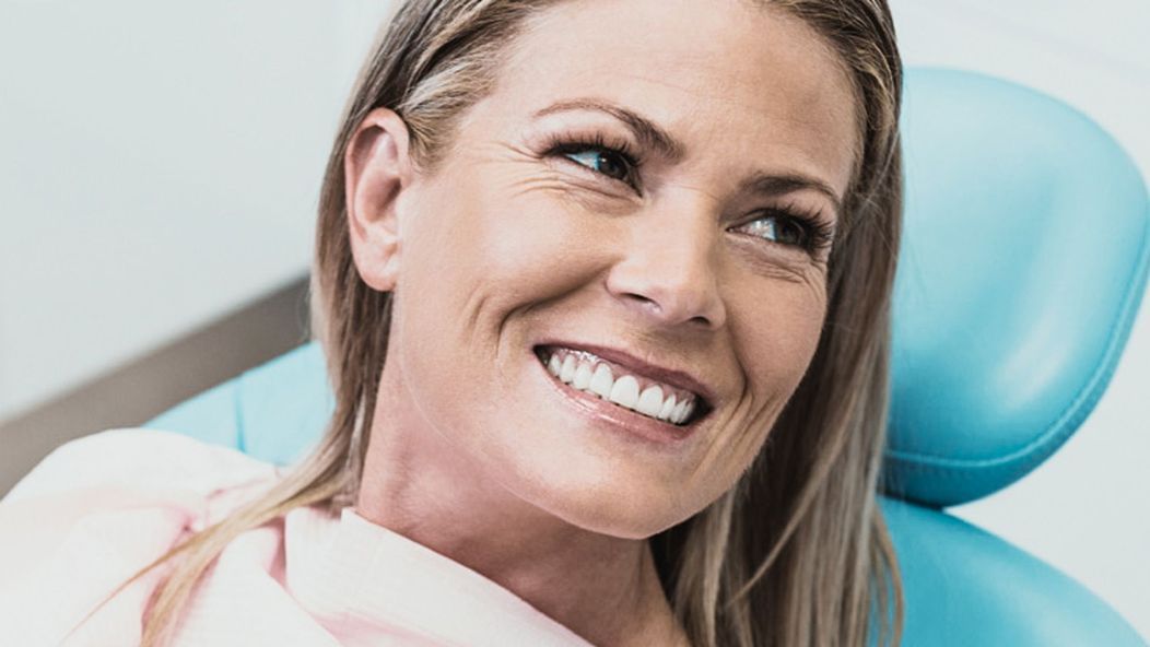 An image of a woman on a dental chair smiling